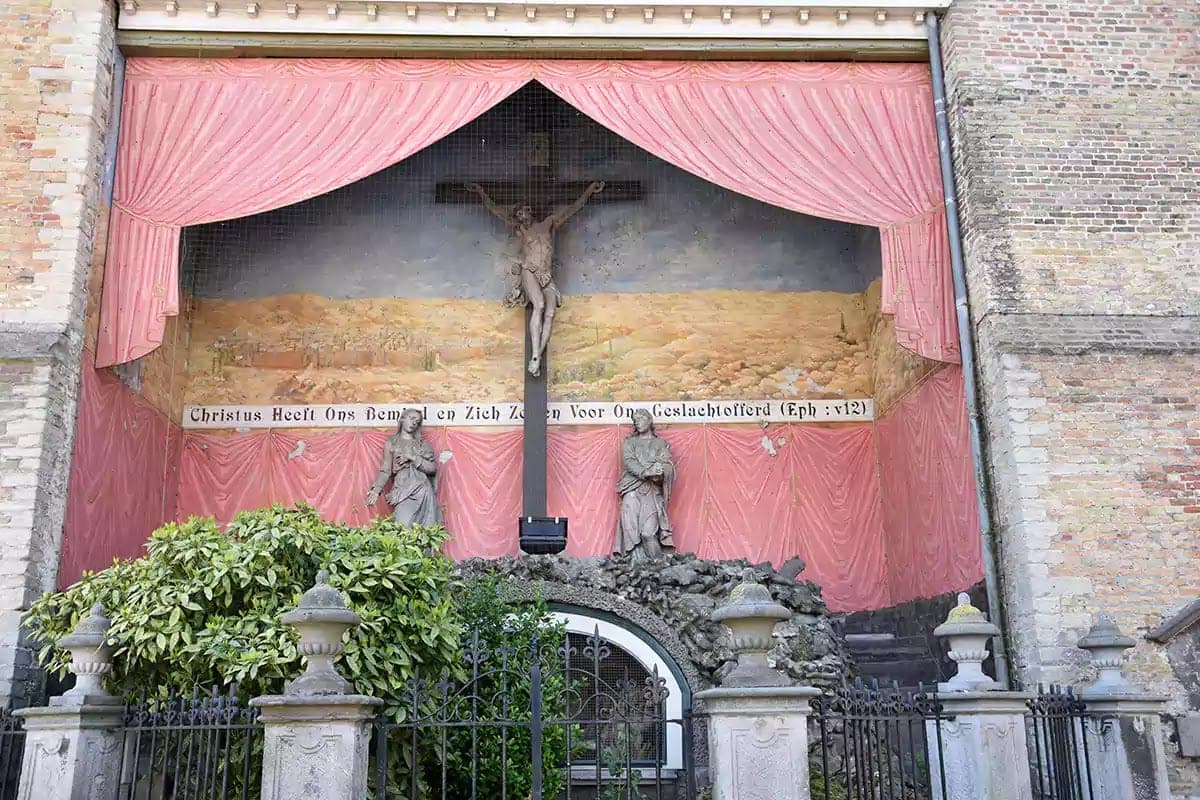 Malovaná kalvárie s nápisem Christus Heeft Ons Bemind na zdi kostela