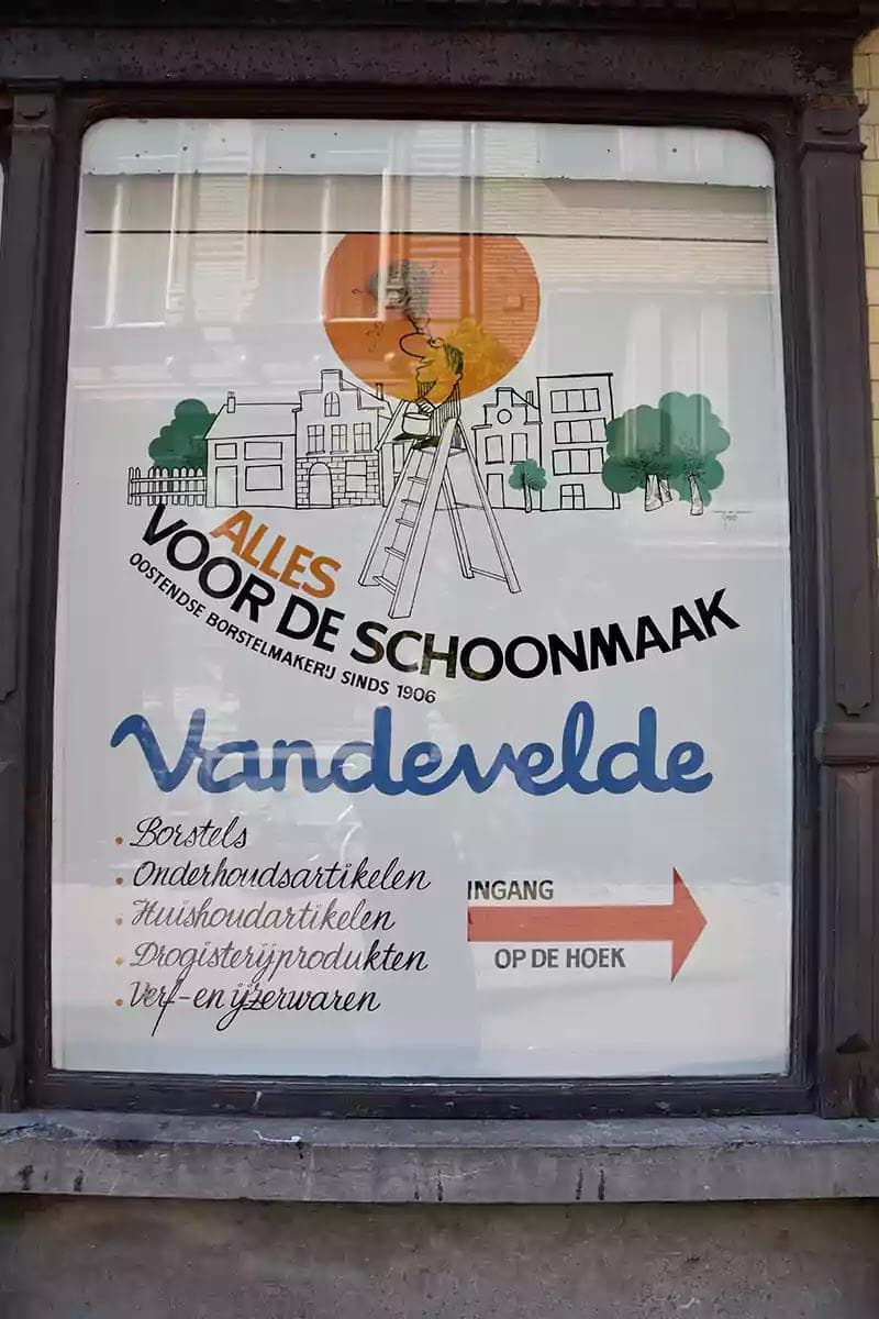 Ručně malovaná výloha drogerie Vandevelde s kresbou a seznamem zboží