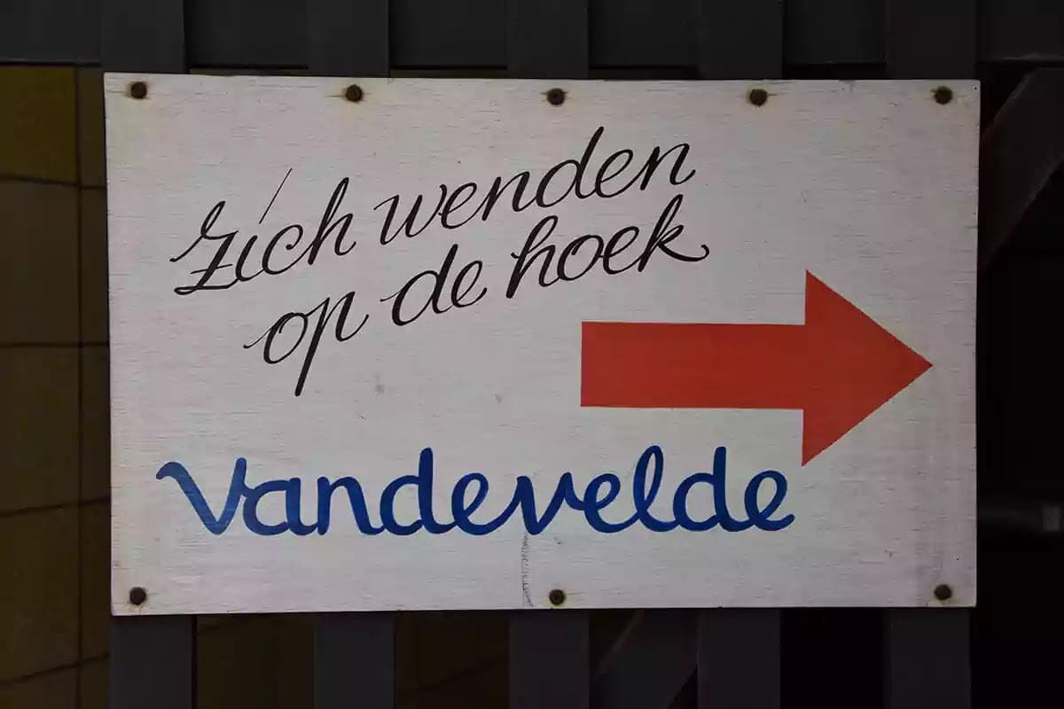 Malovaná cedule se šipkou Zich wenden op de hoek Vandevelde
