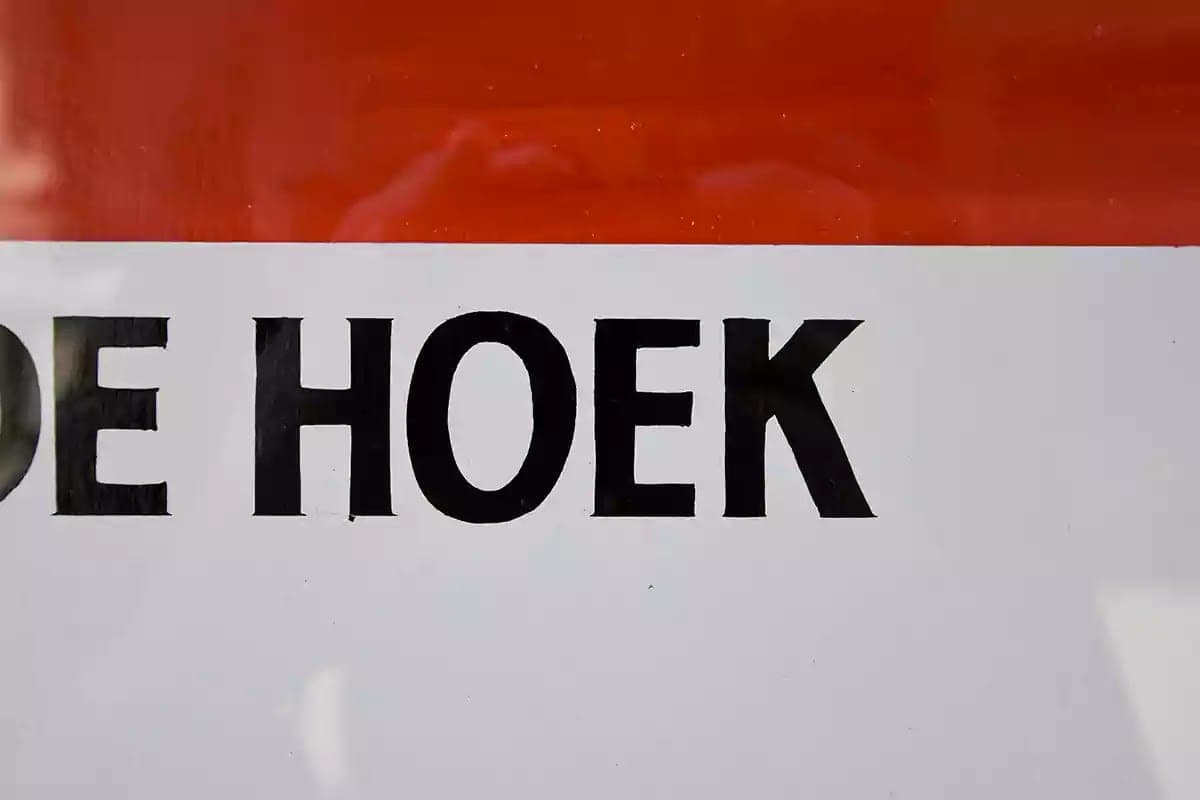 Detail ručně malovaného nápisu DE HOEK pod červeným pruhem