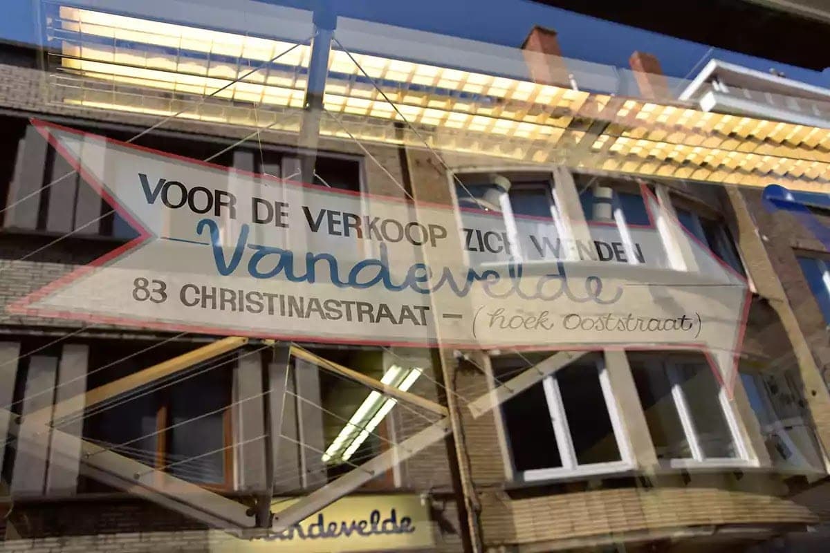 Cedule ve tvaru šipky Voor de verkoop zich wenden Vandevelde v odrazu skla
