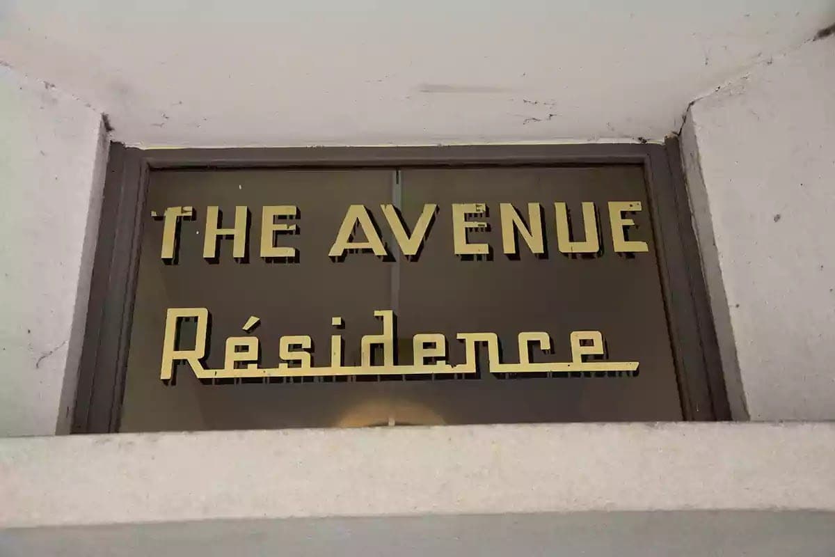 Zlacený nápis The Avenue Résidence na skle nad dveřmi