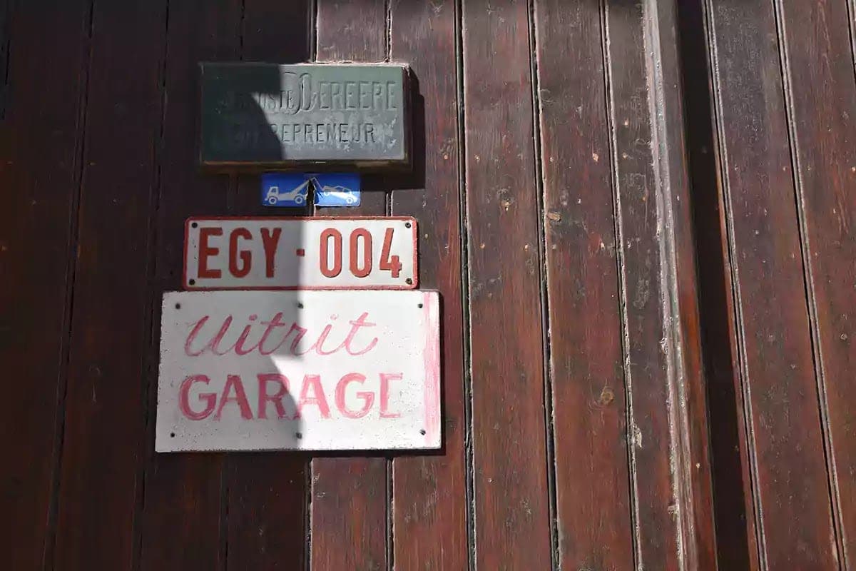 Cedulky na dřevěných vratech s ručně psaným nápisem Uitrit Garage