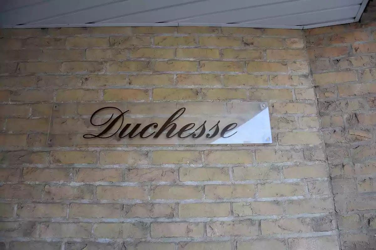 Psací nápis Duchesse na desce na cihlové zdi