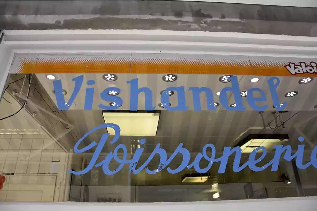 Modrý nápis Vishandel Poissonerie štětcem na výloze rybárny