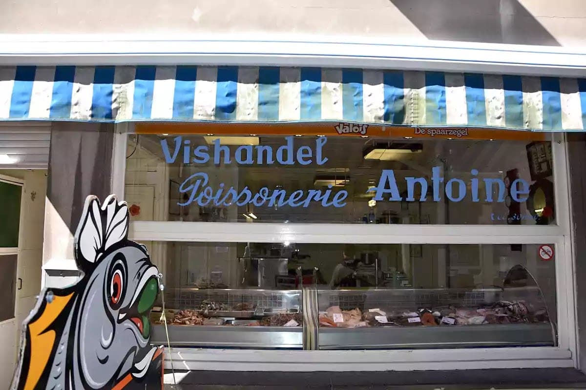 Výloha rybárny Antoine s modrými nápisy a figurkou ryby