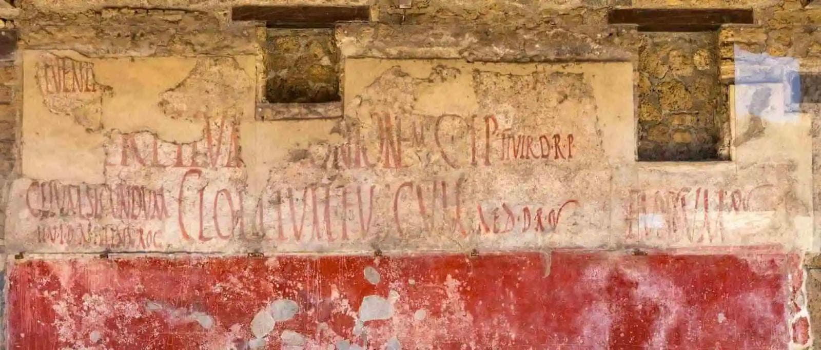 Červené volební nápisy psané štětcem na zdi v Pompejích