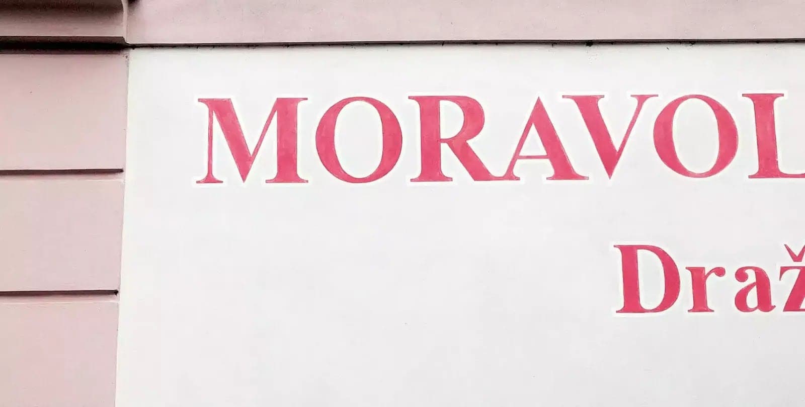 Ručně malovaný červený nápis MORAVOL na fasádě