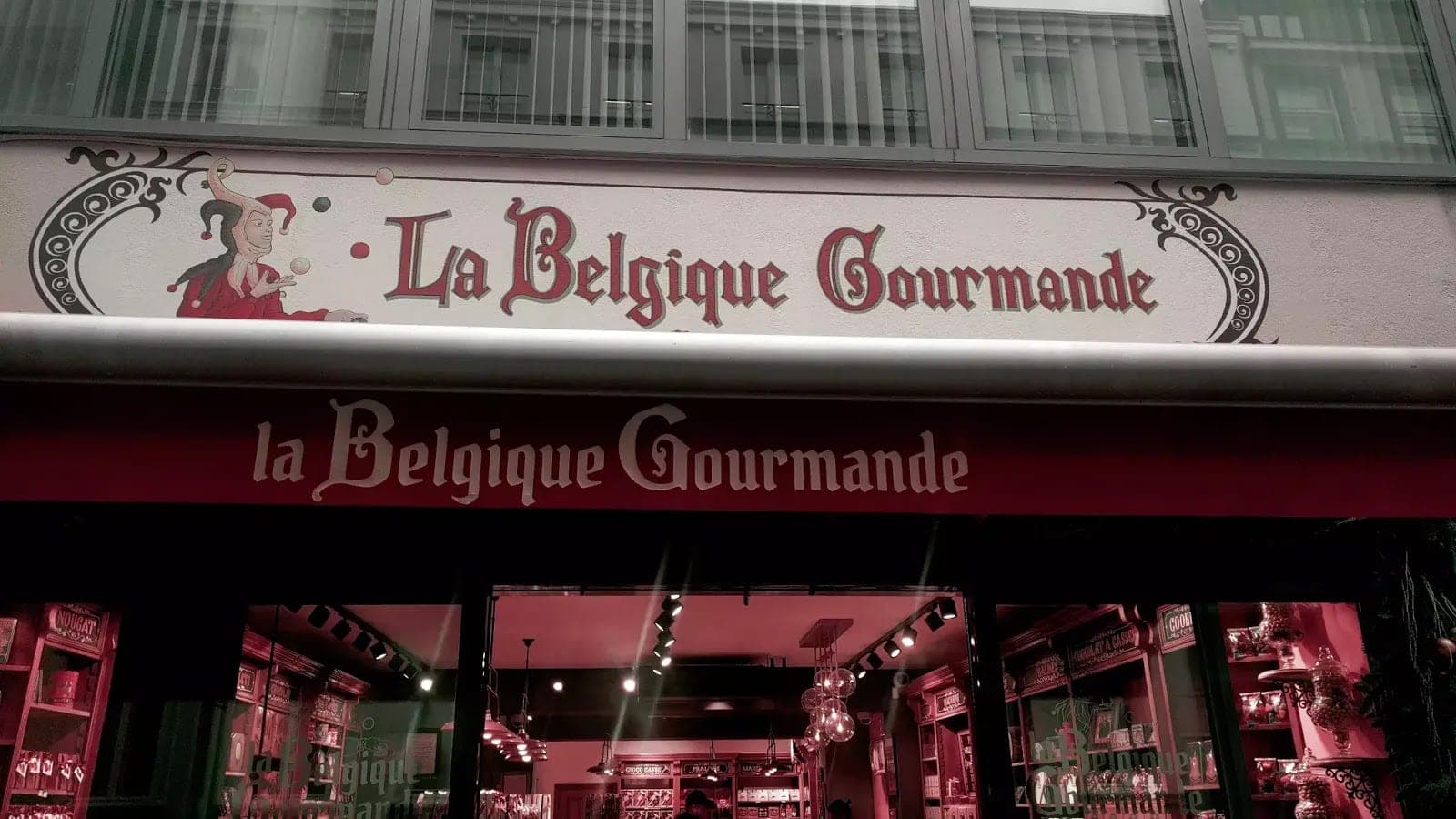 Vývěsní štít La Belgique Gourmande s ozdobným písmem a šaškem