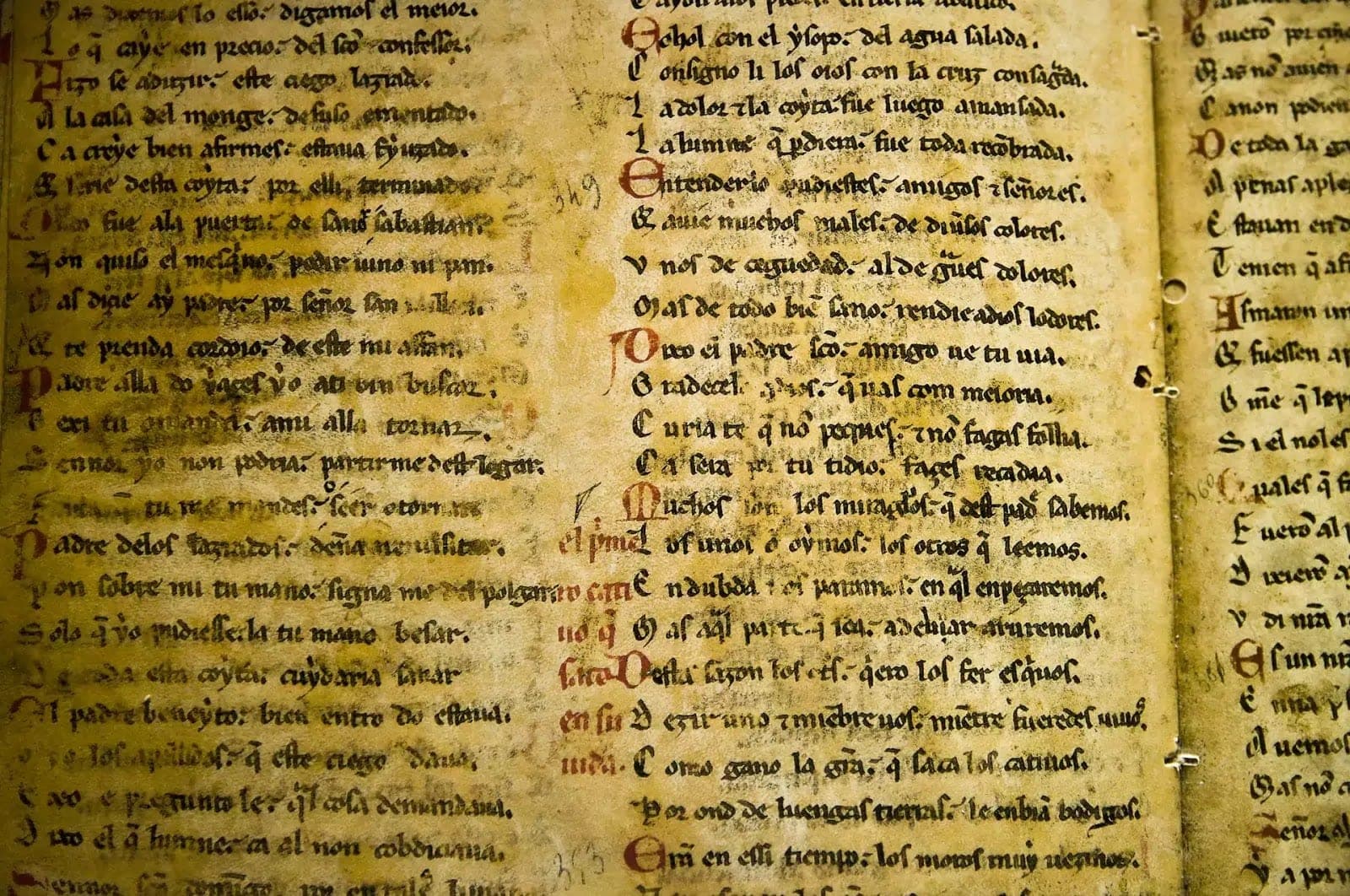 Detail středověkého rukopisu se zažloutlým pergamenem a červenými iniciálami