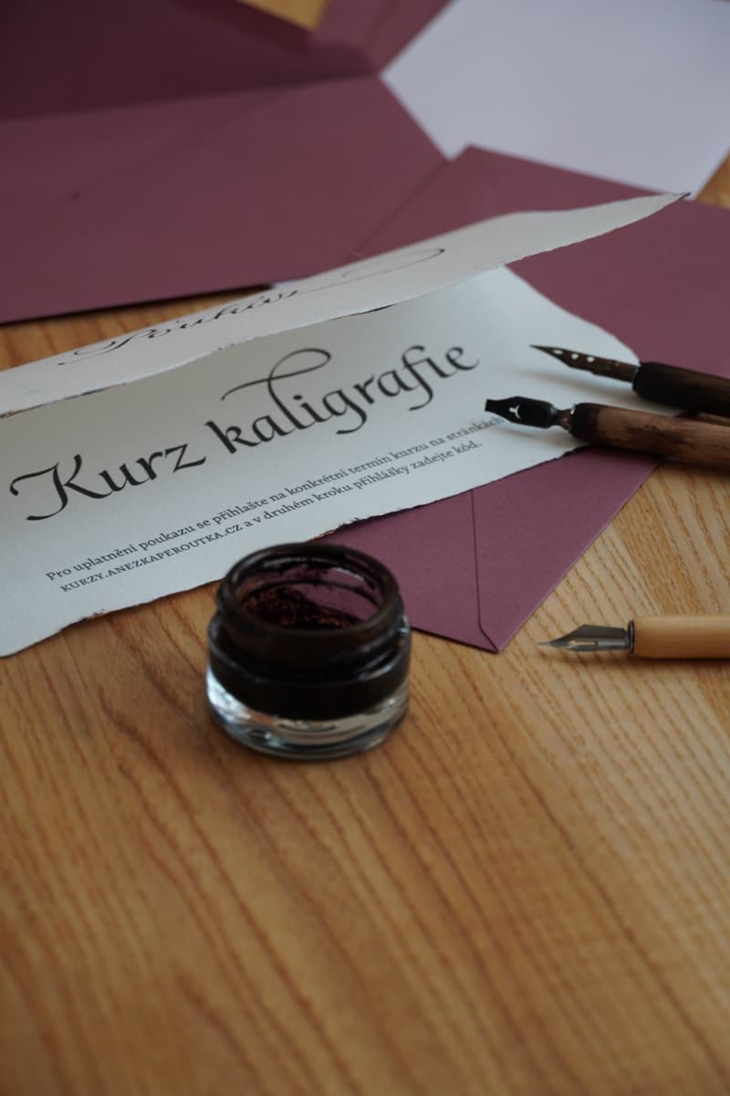 Rozložený poukaz s nápisem Kurz kaligrafie na ručním papíře s natrhaným okrajem
